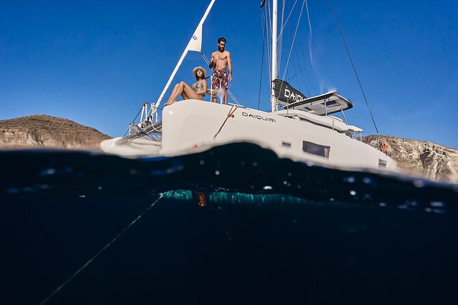 Santorini Oia: Luxury Sunset Cruise with Fresh Fish BBQ & Drinks - Mesa Pigadia Beach: black sand, rocks all around, and boat-only access