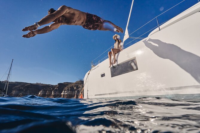 Santorini Oia: Luxury Sunset Cruise with Fresh Fish BBQ & Drinks - Red Beach hour: turquoise water, red rocks, and the main BBQ moment