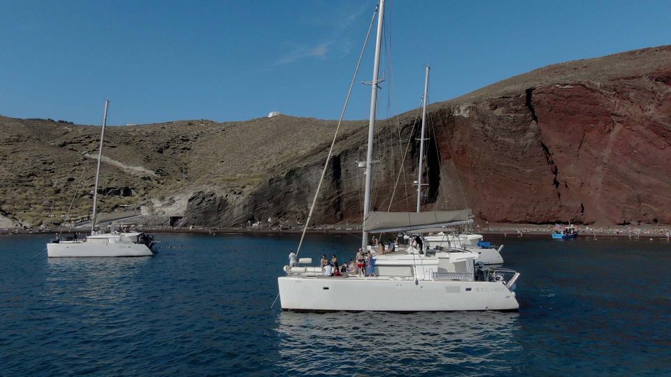 Santorini: Sunset Cruise with Greek Dinner and Transfer - South-coast swim stops at Red and White Beaches